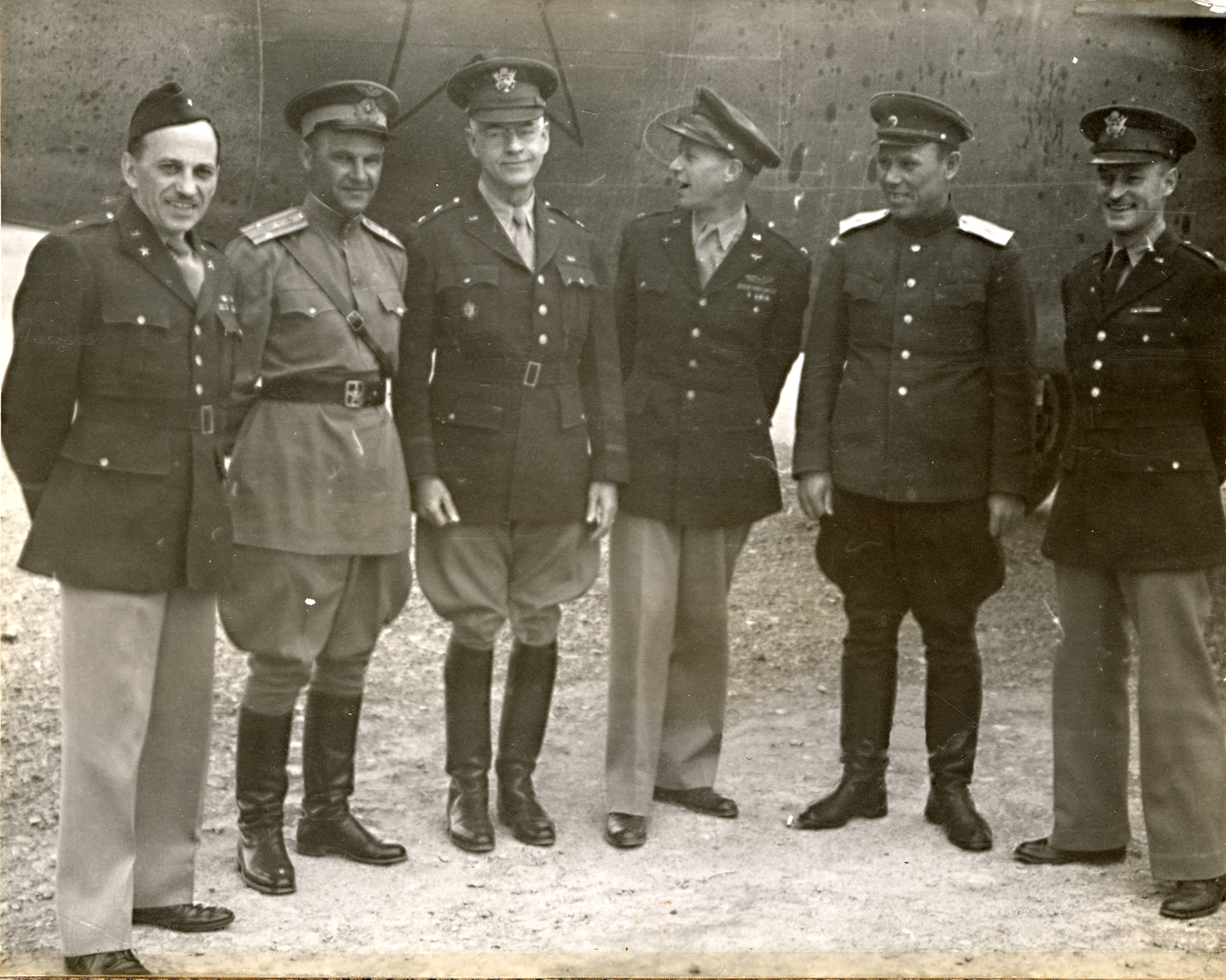 Six military officers stand before an airplane